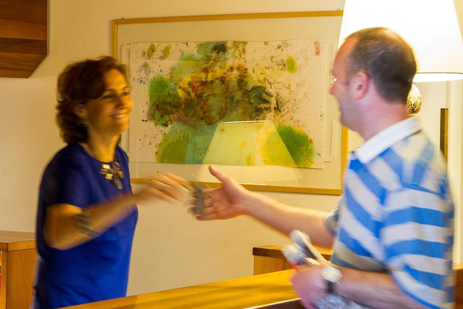 Dos personas en una habitación con una mesa de madera y un cuadro en la pared.