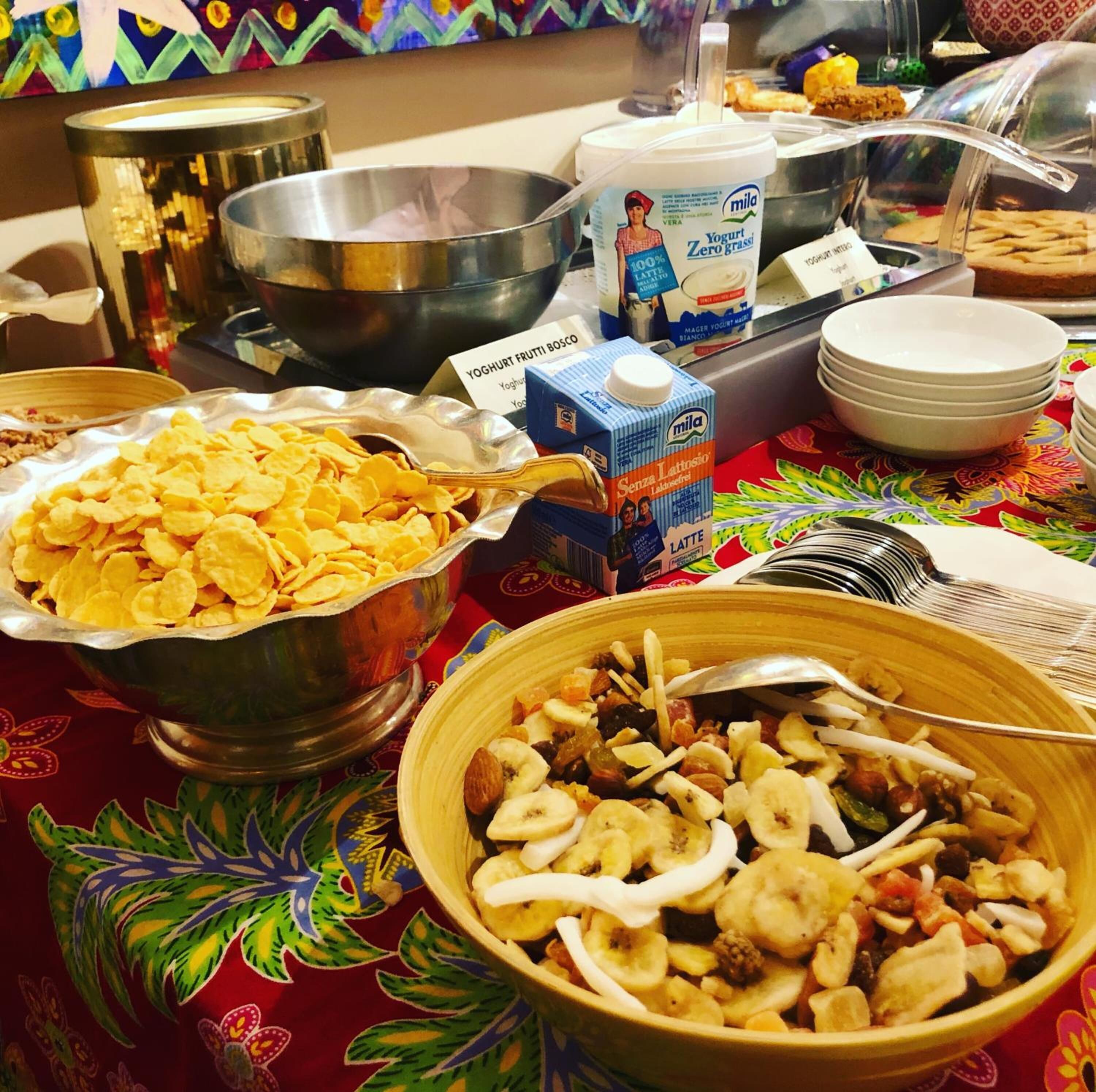 A buffet table with various food items including cereal, yogurt, and a fruit and nut mix.