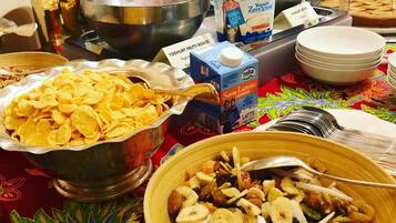 A buffet table with various food items including cereal, yogurt, and a fruit and nut mix.