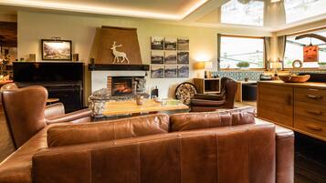 A cozy living room with a fireplace, leather sofa, wooden coffee table, and a television.