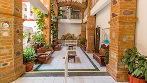 A spacious indoor courtyard with brick walls, wooden furniture, and potted plants.