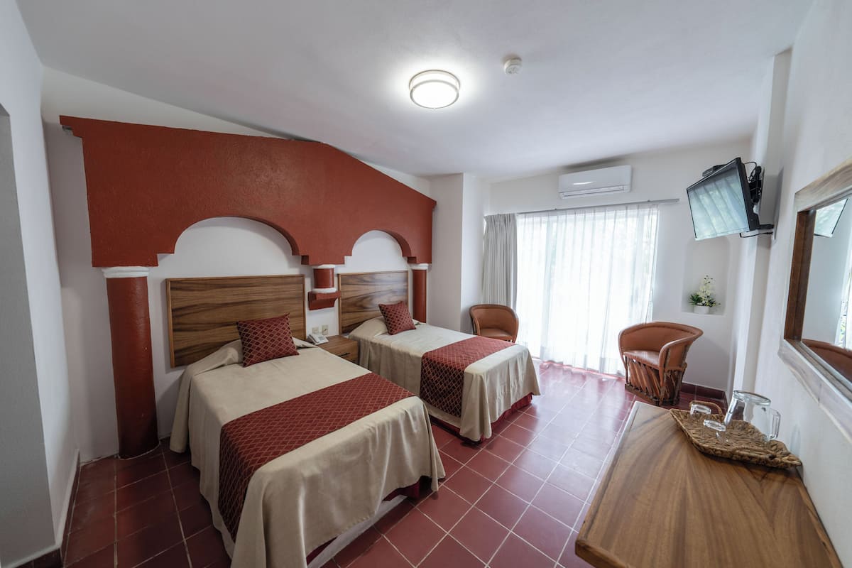Una habitación de hotel con dos camas, un cabecero de madera, un televisor y una silla.
