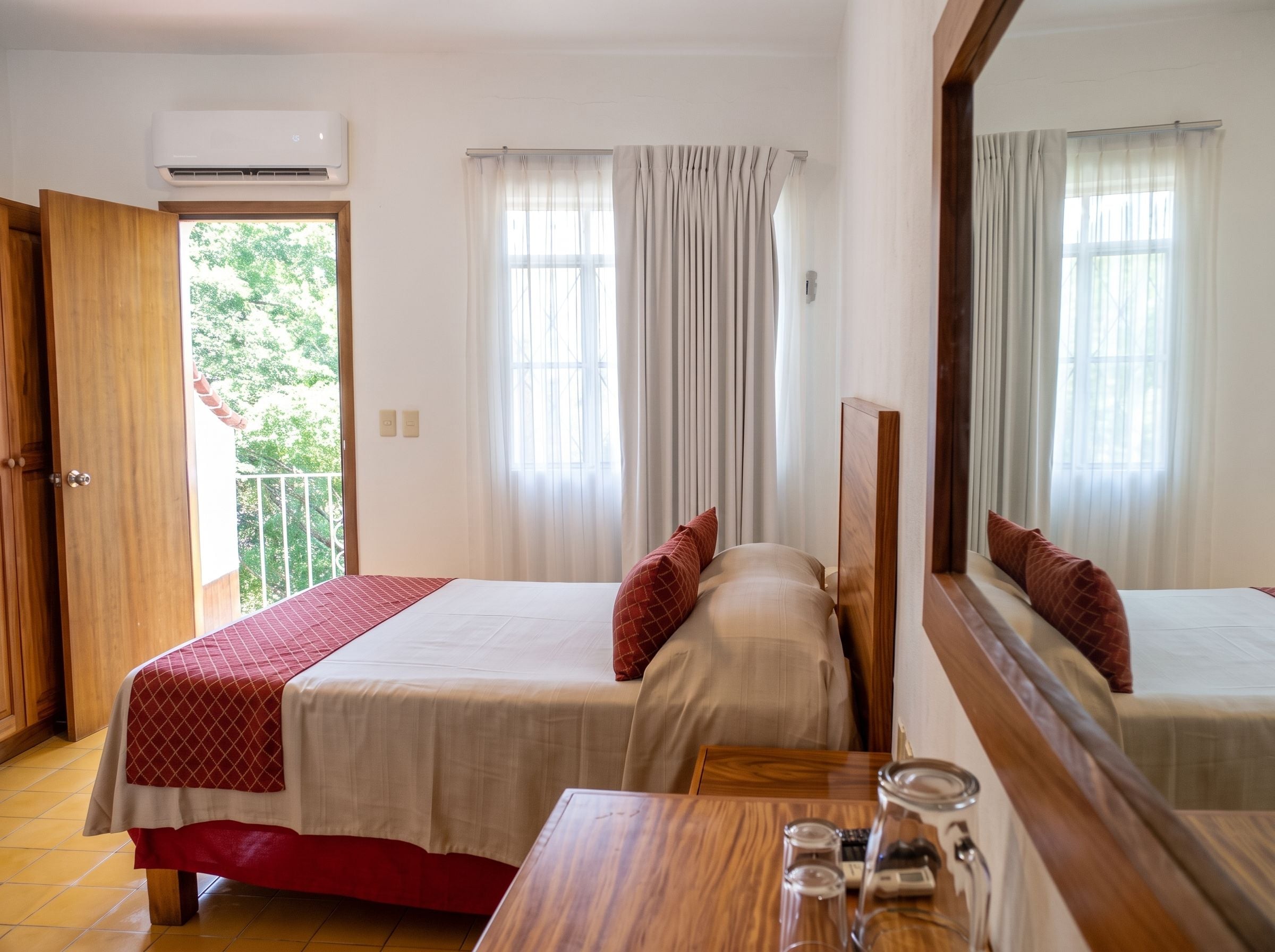 Habitación de hotel con dos camas, una mesa de madera y un balcón.