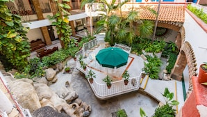 A courtyard with a central seating area, potted plants, and a tiled floor.