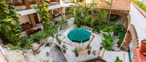 A courtyard with a central seating area, potted plants, and a tiled floor.