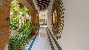 A corridor with brick walls, green-striped tiles, and a decorative mirror.