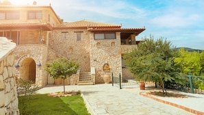 A stone building with a tiled roof, a staircase, and a garden area. - Villas Cavo Marathia (Zakynthos)