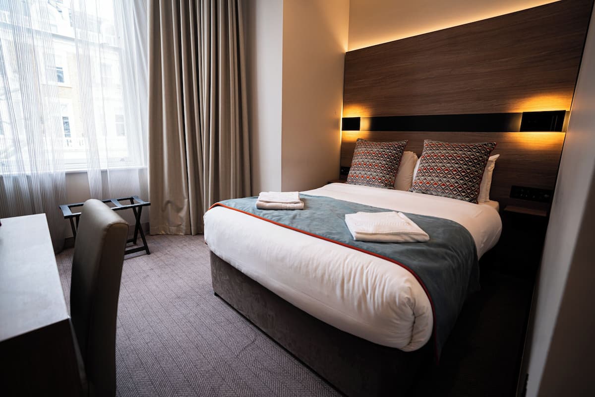 A hotel room with a bed, a desk, and a chair.