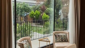 Een hoekappartement met een grote schuifglazen deur die leidt naar een balkon. Op het balkon staan twee stoelen en een kleine tafel.