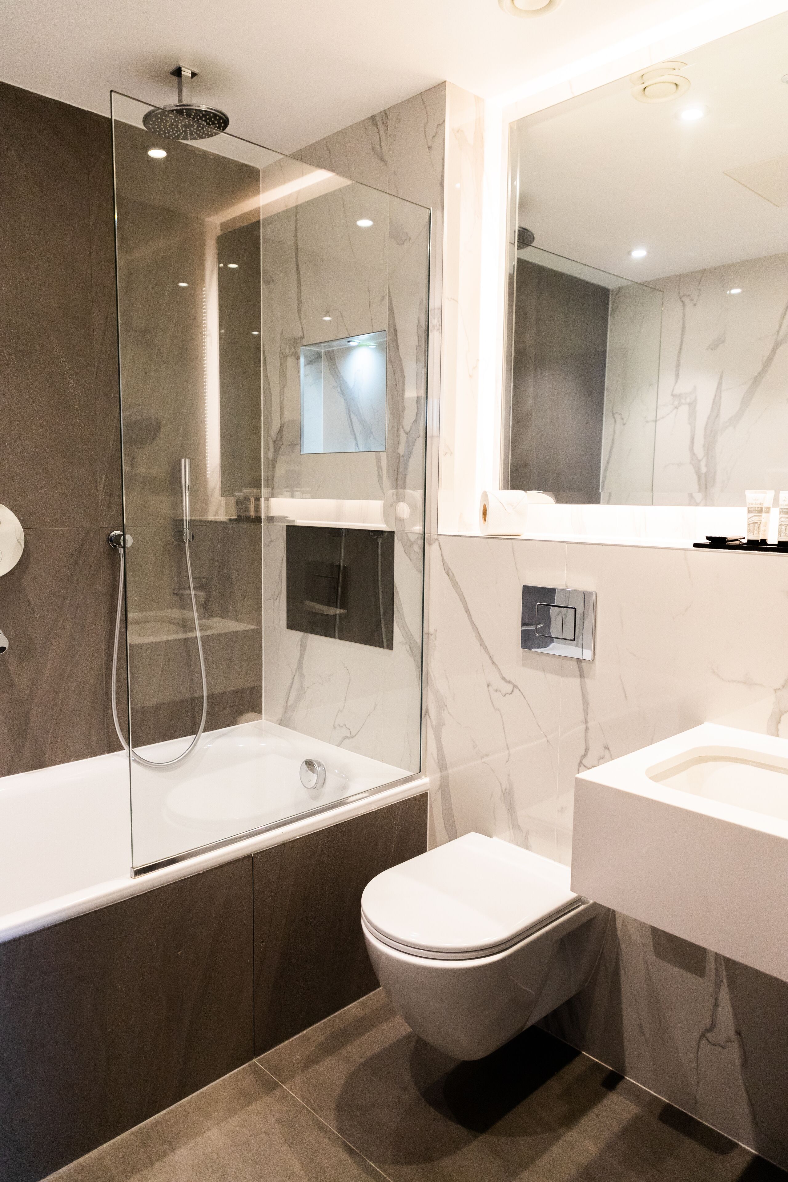 A modern bathroom with a glass-enclosed shower, a toilet, and a sink.