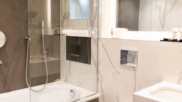 A modern bathroom with a glass-enclosed shower, a toilet, and a sink.