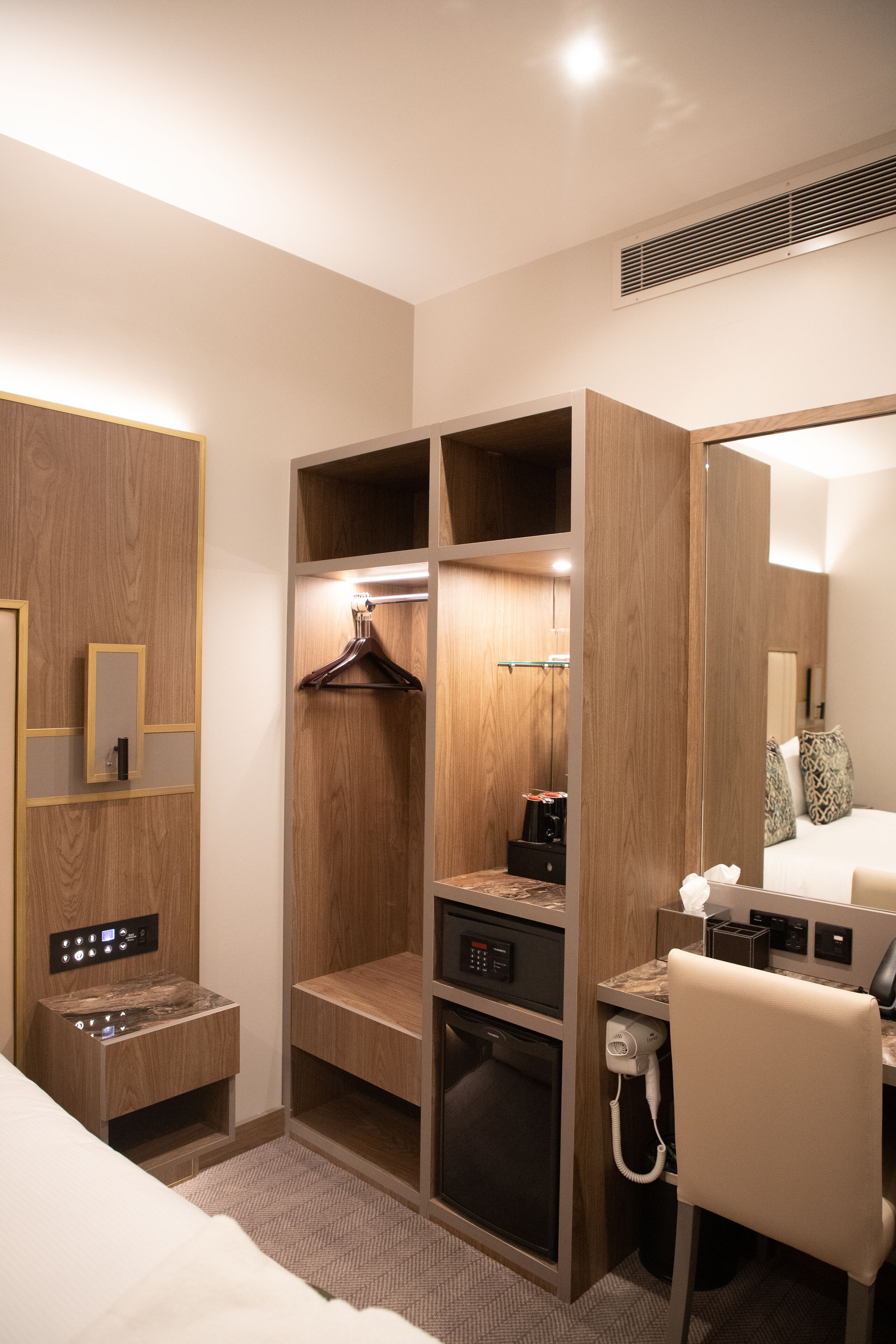 Ein Hotelzimmer mit einem Holzschrank, einem Schreibtisch mit Telefon und einem Bett.