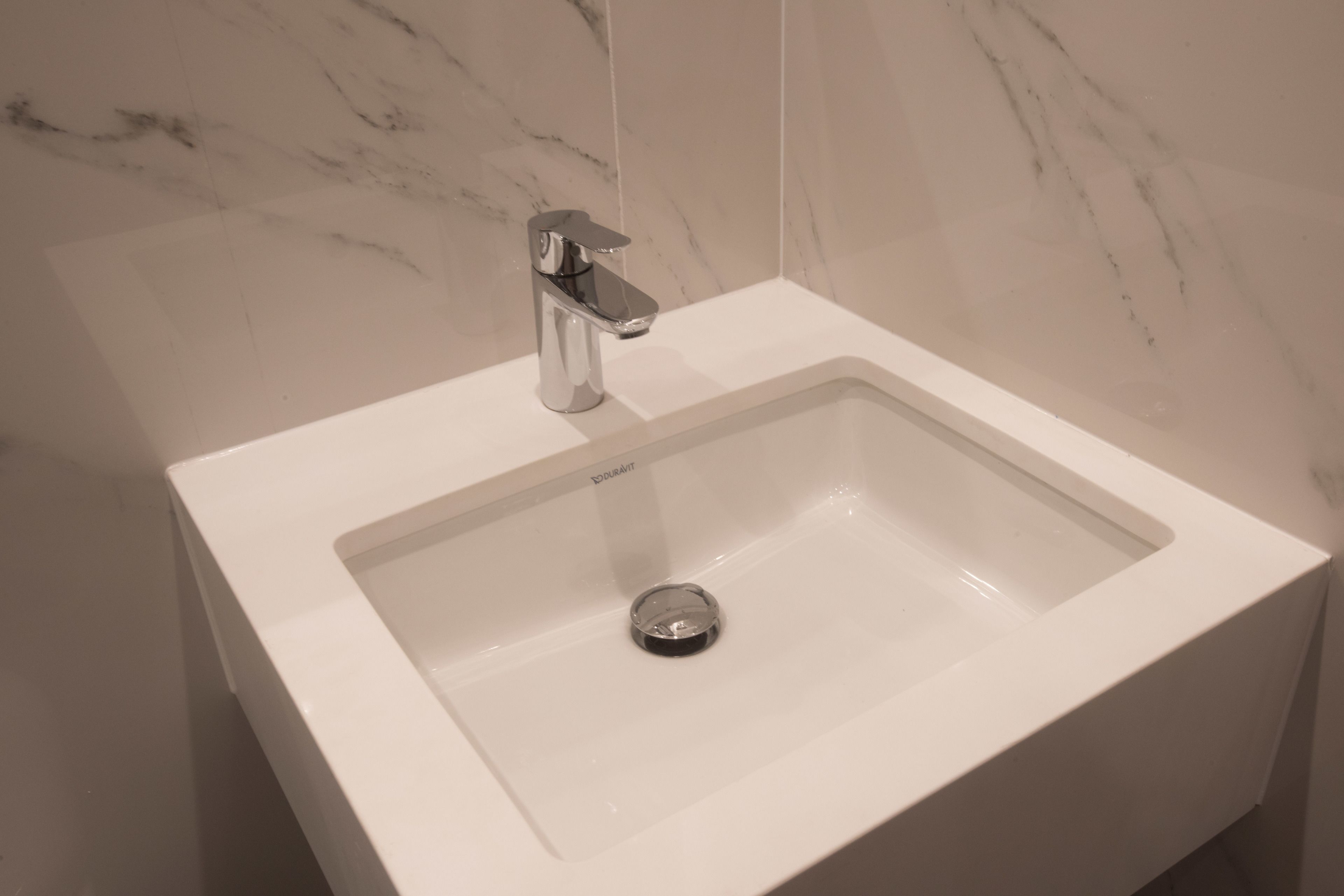 Un lavabo blanc pour la salle de bain, avec un robinet chromé et un drain.