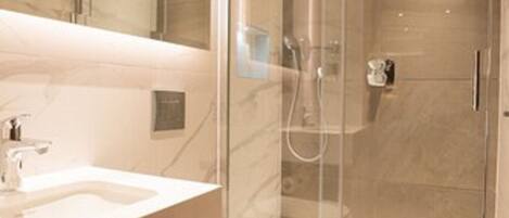 A modern bathroom with a glass-enclosed shower, a marble-tiled vanity, and a toilet.
