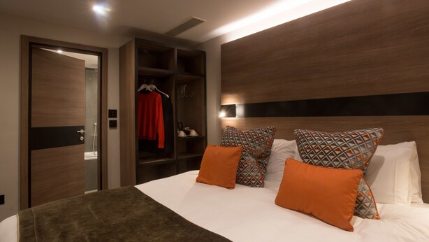 Een moderne hotelkamer met een groot bed, een kledingkast en een inbouwkleedkamer.