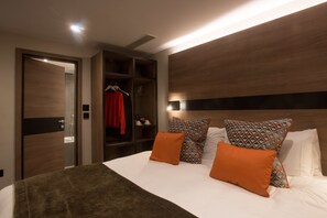 Una habitación de hotel moderna con una cama grande, un armario y una estantería empotrada.