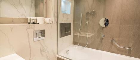 A modern bathroom with a glass-enclosed shower, a separate toilet, and a large bathtub.
