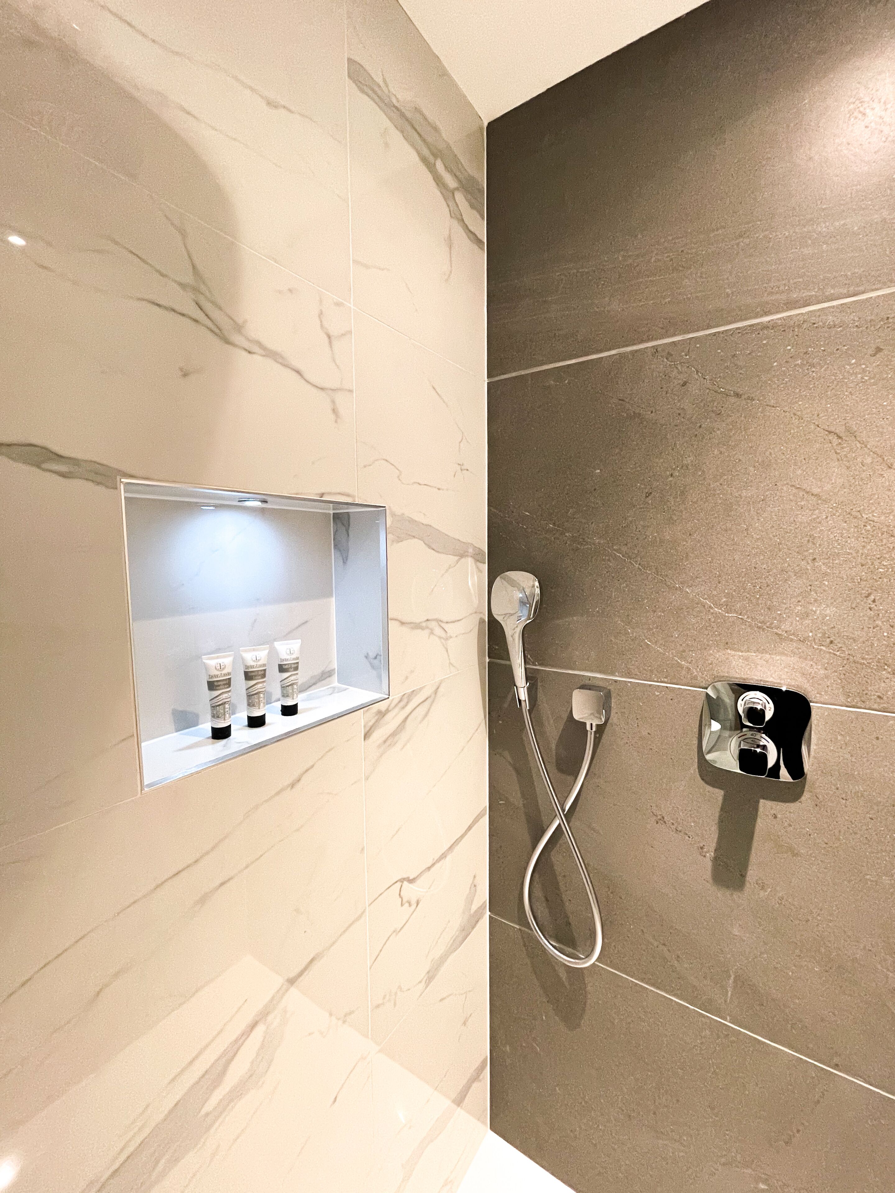 A bathroom with a marble vanity, a shower, and a towel rack.