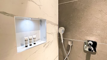 A bathroom with a marble vanity, a shower, and a towel rack.
