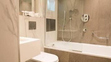 Un baño moderno con cabina de ducha de vidrio, inodoro blanco y suelo de baldosas de mármol.