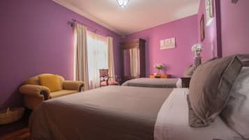 Une chambre avec deux lits, une chaise, une table de chevet et une lampe.