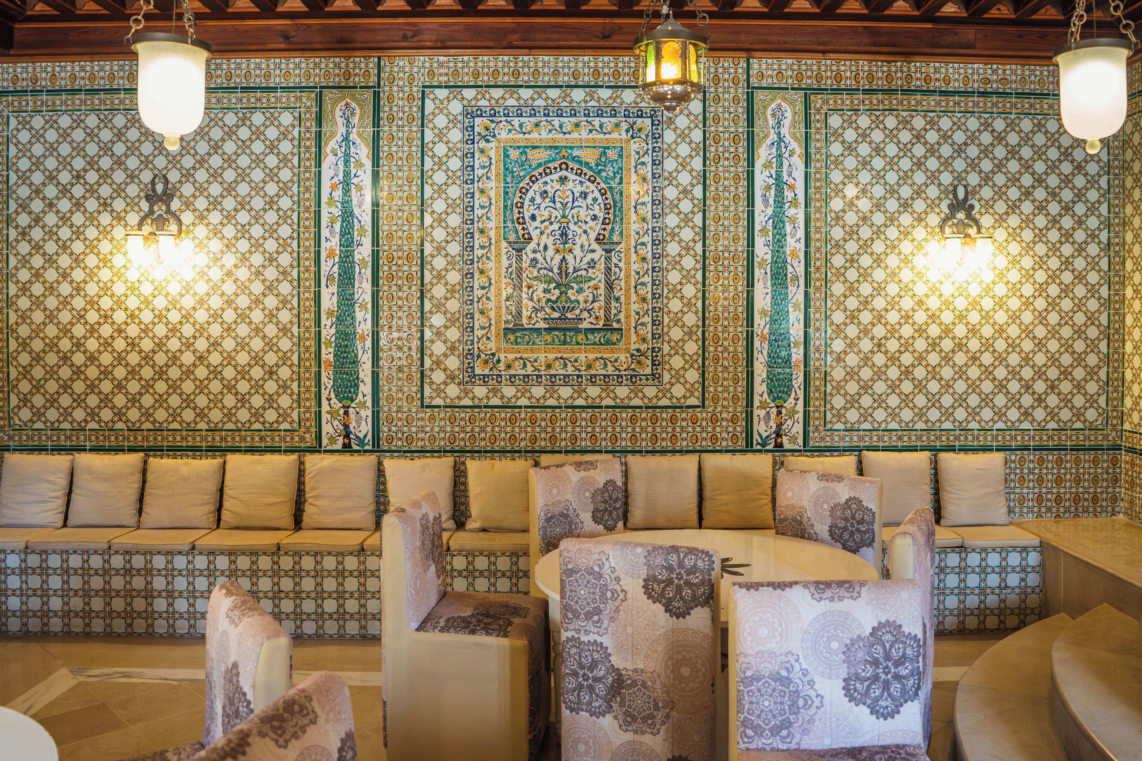 A room with patterned tile walls, a sofa, and chairs.