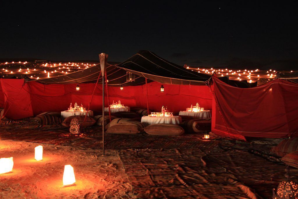 A series of tents with tables set up for dining, surrounded by a campfire area.