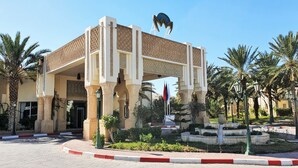 A building with a tiled roof, a large sign, and palm trees.