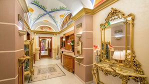 A luxurious hallway with ornate gold furniture, a large mirror, and a decorative ceiling. - Hotel Forte (Rome)