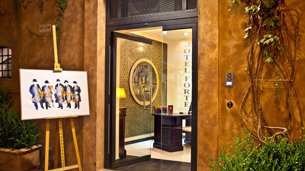 A hotel entrance with a glass door, a framed portrait, and a potted plant. - Hotel Forte (Rome)