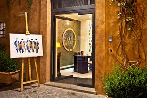 Entrada de hotel con puerta de vidrio, un retrato en marco y una planta en maceta.