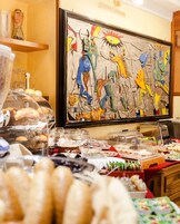 Un área de bufé con diferentes alimentos y un cuadro abstracto grande en la pared.