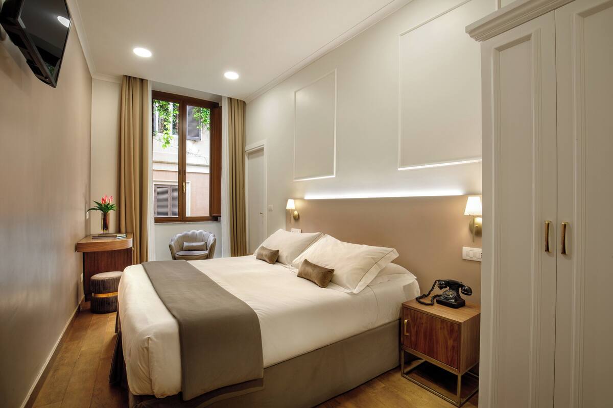 Una camera d'albergo con un letto grande, un comodino, una lampada e un telefono.