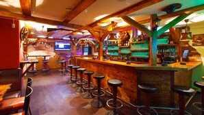 A bar area with wooden beams, stools, and a bar counter stocked with bottles and glasses. - Hotel Ochsen (Bad Saulgau)