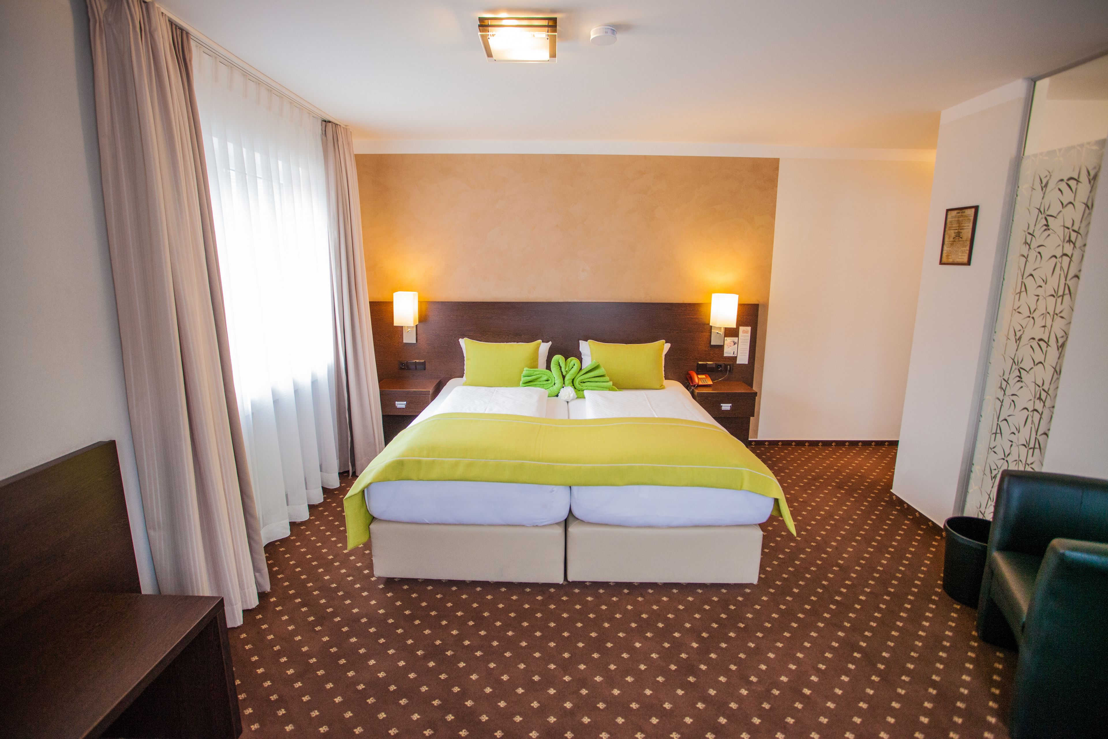Une chambre d’hôtel avec un grand lit, deux tables de chevet, une petite table, un bureau et une chaise.