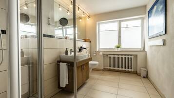A modern bathroom with a glass shower enclosure, a vanity with a sink, and a toilet.