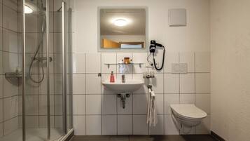 A bathroom with a glass-enclosed shower, a sink with a mirror above it, and a toilet.