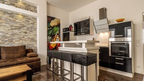 A modern kitchen with a stone wall, a brown leather sofa, and a wooden table. - Hotel Ochsen (Bad Saulgau)