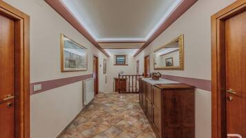 Un pasillo con puertas de madera, un radiador, piso de baldosas y un mostrador con una cesta.