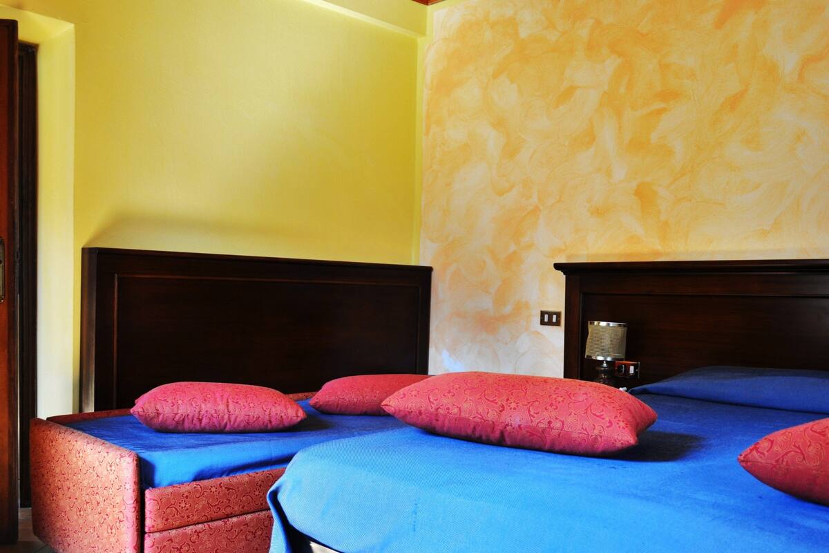 Ein Hotelzimmer mit zwei Betten, jeweils mit blauer und roter Bettwäsche, und einem Holzkopfende.