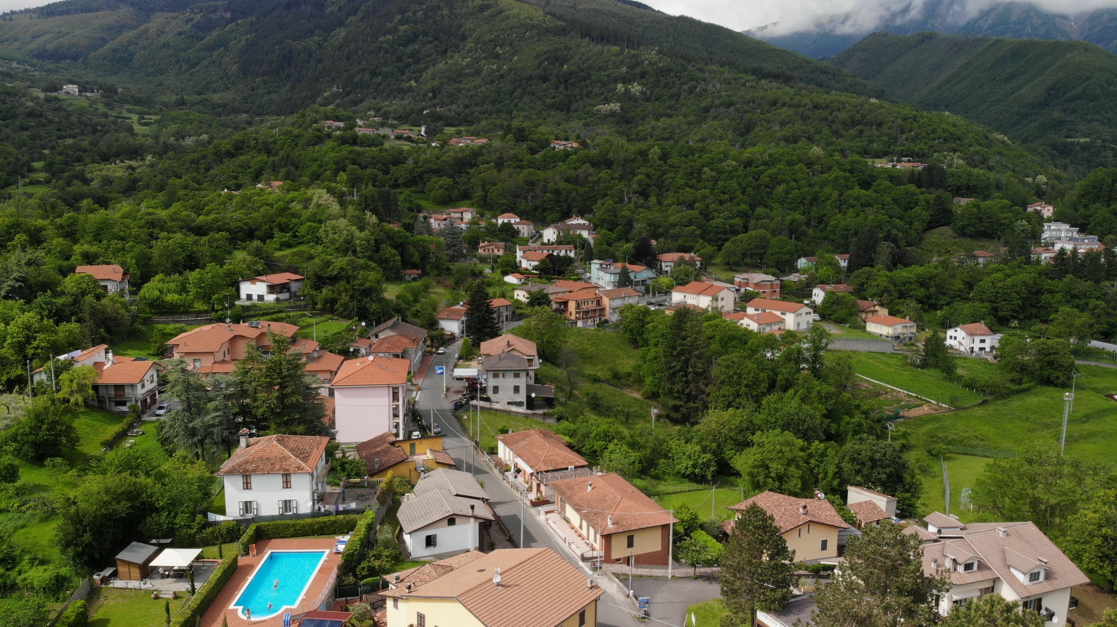 A residential area with houses, a swimming pool, and a mountainous backdrop.