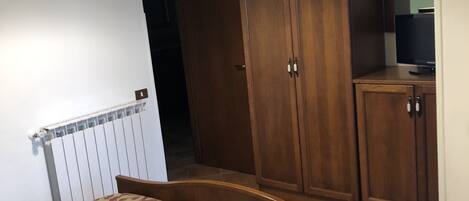 Un dormitorio con cama, armario y televisor sobre un mueble.