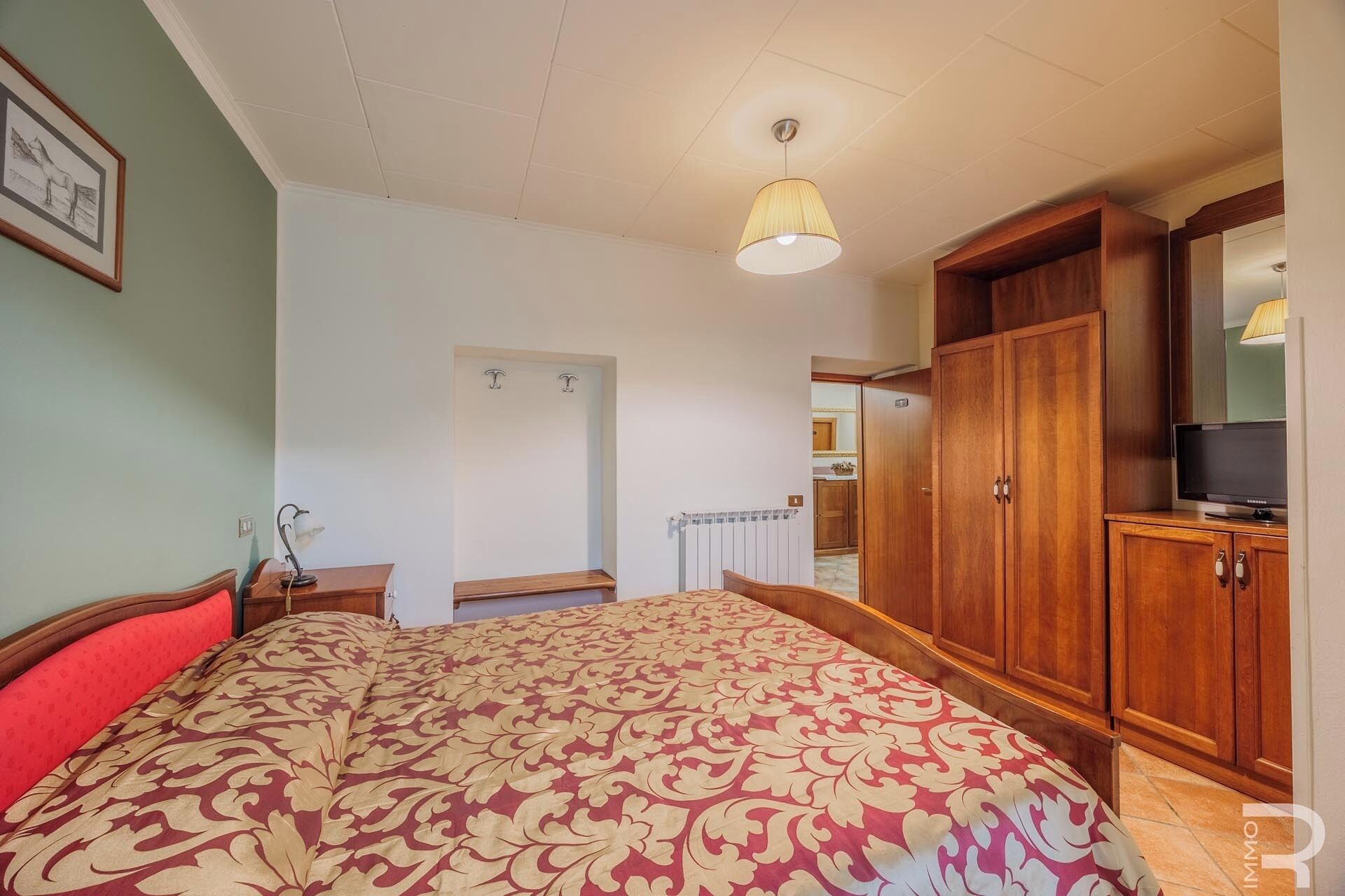 Un dormitorio con una cama, un armario de madera y un televisor.