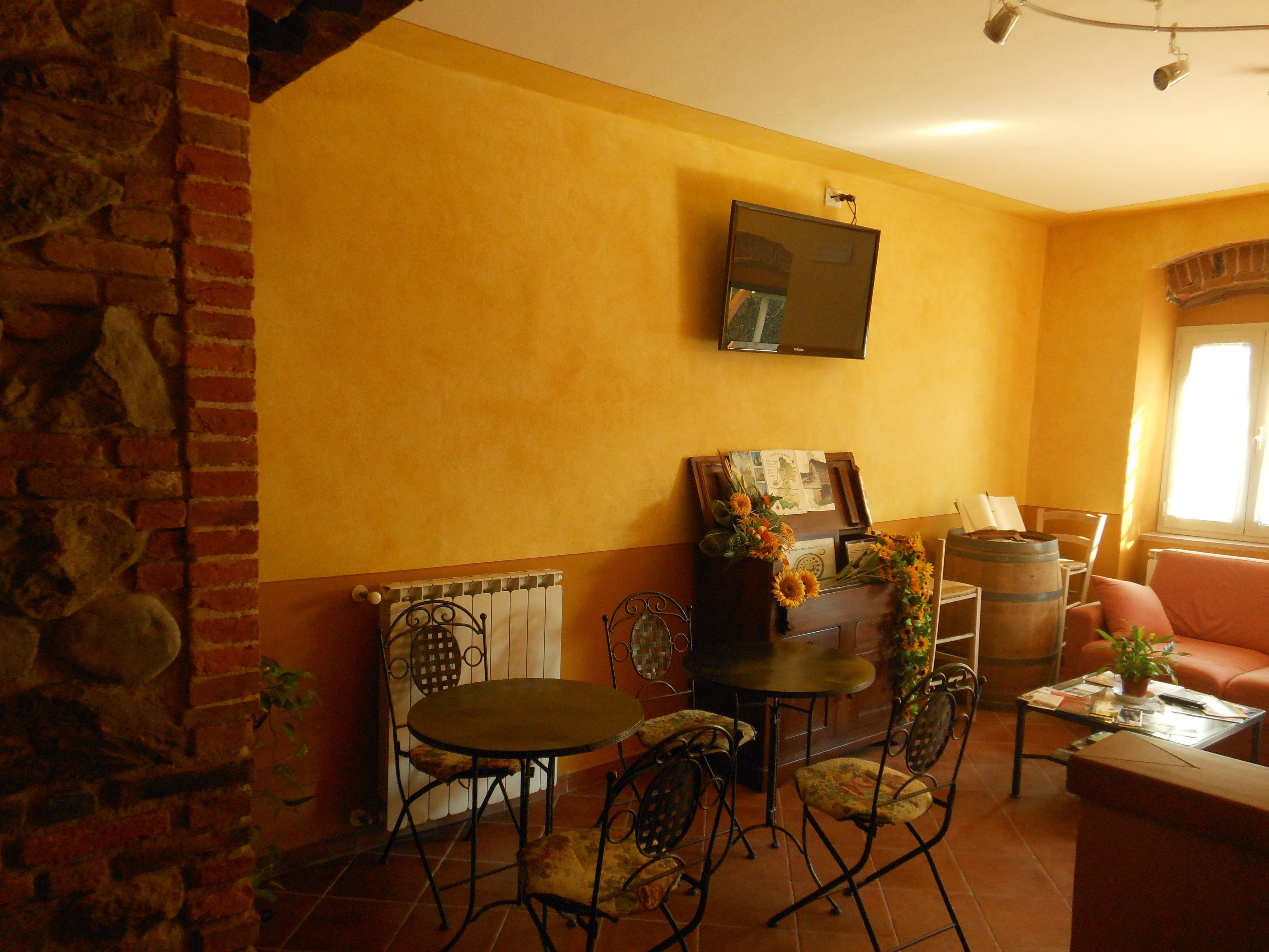 Un salon chaleureux avec un mur en briques, une cheminée, un téléviseur et un coin salon confortable comprenant un canapé et des fauteuils.