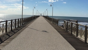A long, straight pier with metal railings and street lamps, leading to the ocean. - Hotel Mirage Versilia (Pietrasanta)