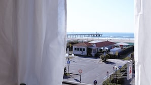 A coastal view with a pier, a building with a red roof, and a parking area. - Hotel Mirage Versilia (Pietrasanta)
