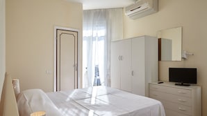 A bedroom with a bed, a wardrobe, a television, and a window with curtains. - Hotel Mirage Versilia (Pietrasanta)