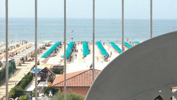 A beach view with rows of umbrellas and beach chairs, a clear sky, and the sea in the background. - Hotel Mirage Versilia (Pietrasanta)
