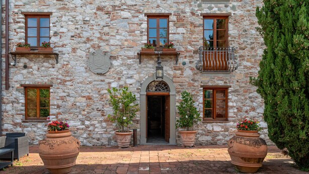 A stone building with multiple windows, a central entrance, and potted plants. - Villa Corte Degli Dei (Lucca)
