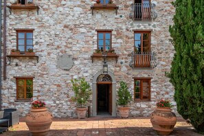 A stone building with multiple windows, a central entrance, and potted plants. - Villa Corte Degli Dei (Lucca)
